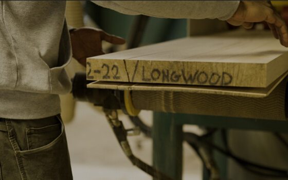 A persons hands getting ready to pick up a plank of wood.